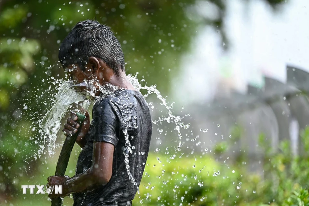 Trẻ em chơi đùa với nước để giải nhiệt trong ngày nắng nóng tại Ấn Độ, ngày 28/5. (Ảnh: AFP/TTXVN)