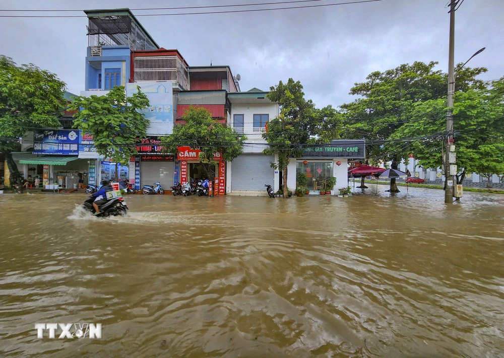 Nước ngập sâu khiến cho các phương tiện giao thông đi lại khó khăn, ảnh hưởng đến sinh hoạt của người dân. (Ảnh: Xuân Tư/TTXVN)