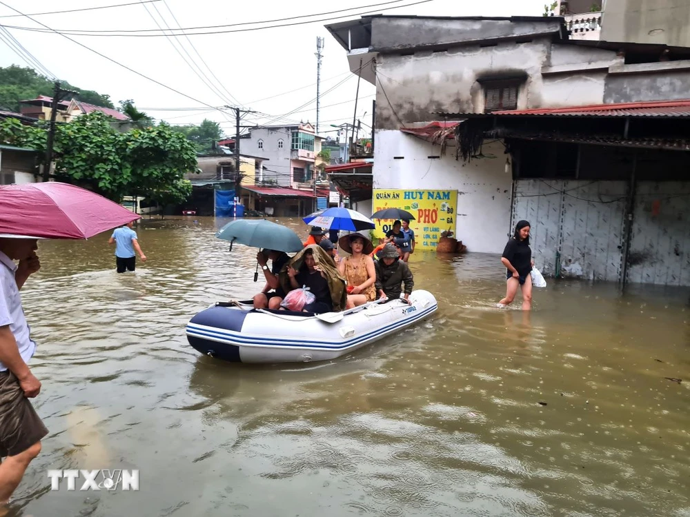 Cán bộ, chiến sỹ Công an tỉnh Hà Giang hỗ trợ di chuyển người và tài sản bị ngập sâu trong nước. (Ảnh: Nguyễn Lân/TTXVN phát)