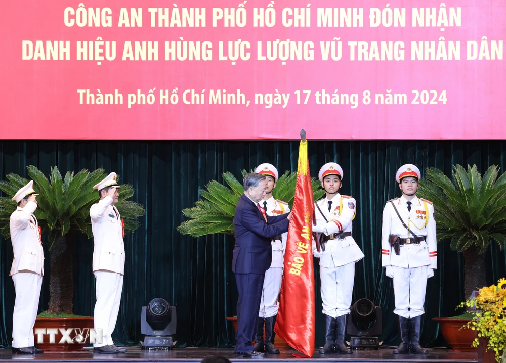 Tổng Bí thư, Chủ tịch nước Tô Lâm gắn Huy hiệu Anh hùng lực lượng vũ trang nhân dân lên lá cờ truyền thống của Công an Thành phố Hồ Chí Minh. (Ảnh: Lâm Khánh/TTXVN)