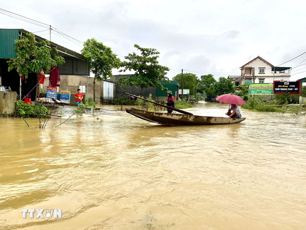 Người dân xã Kim Hoa, huyện Hương Sơn sử dụng thuyền để di chuyển trong vùng ngập nước. (Ảnh: Hữu Quyết/TTXVN)