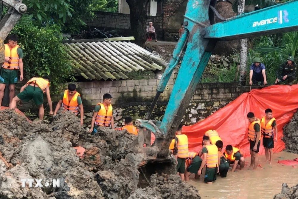 Hơn 100 cán bộ, chiến sỹ Trung đoàn 762 Bộ Chỉ huy Quân sự tỉnh Thanh Hóa dầm mình trong nước lũ nỗ lực khắc phục sự cố. (Ảnh: TTXVN phát)