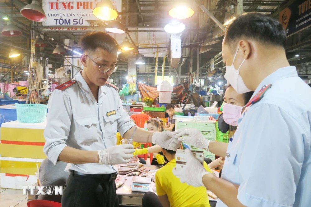 Nhân viên Sở An toàn thực phẩm Thành phố Hồ Chí Minh lấy mẫu kiểm nghiệm nhanh tại chợ đầu mối Bình Điền. (Ảnh: Đinh Hằng/TTXVN)