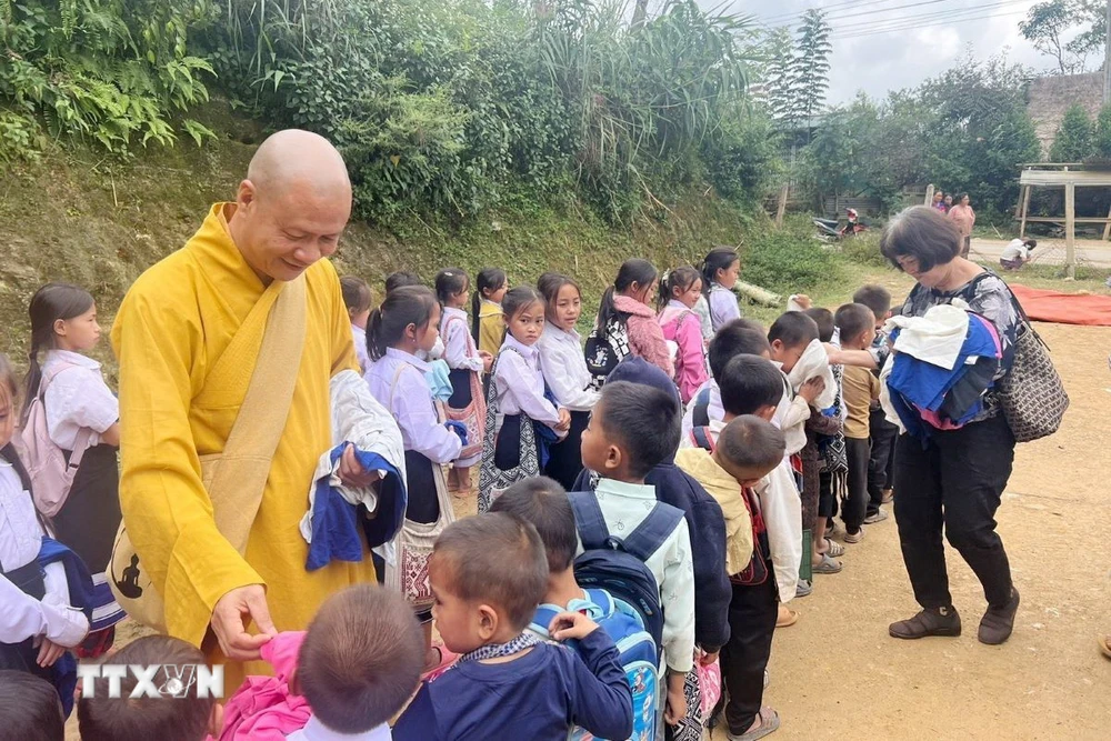 Thượng tọa Thích Minh Quang, Trưởng ban Điều phối và hợp tác Giáo hội Phật giáo Việt Nam tại Lào phát quần áo cho những trẻ em bị ảnh hưởng do lũ lụt ở Lào. (Ảnh: TTXVN phát)