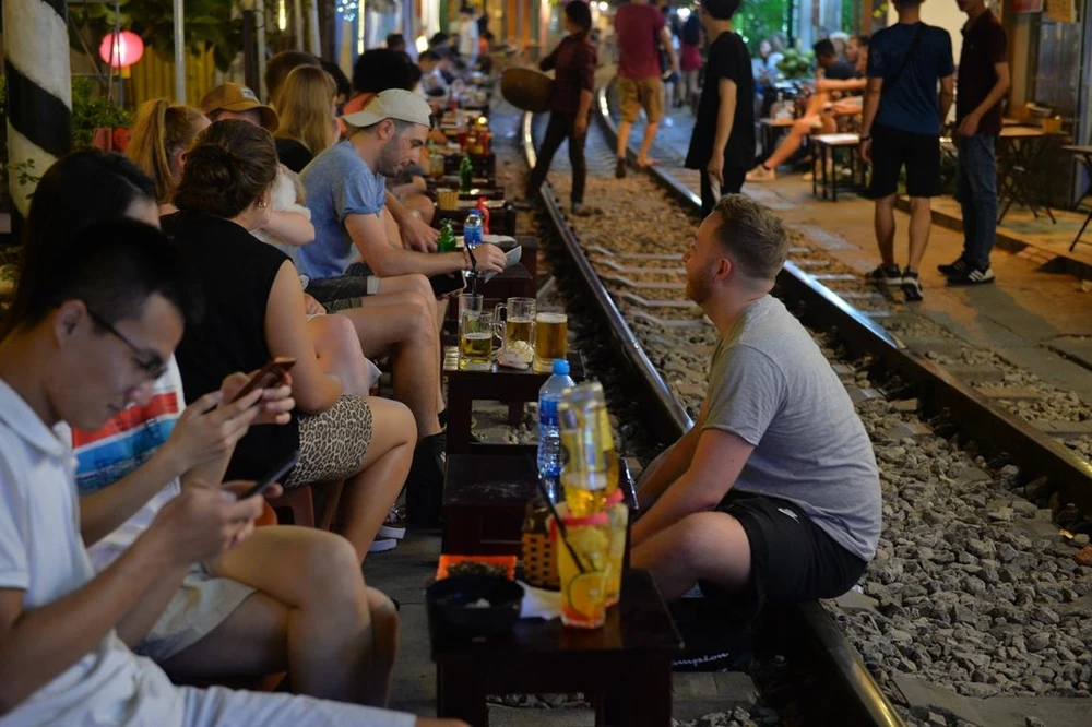Trước khi bị đóng cửa, nhiều du khách đã đến Phố càphê đường tàu để trải nghiệm cảm giác ngồi uống nước sát với đoàn tàu chạy qua. (Ảnh: Hoàng Anh/Vietnam+)