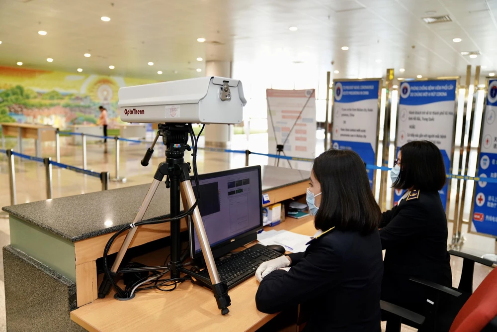 Nhân viên kiểm dịch y tế do thân nhiệt hành khách tại sân bay Nội Bài. (Ảnh: Phan Công/Vietnam+)