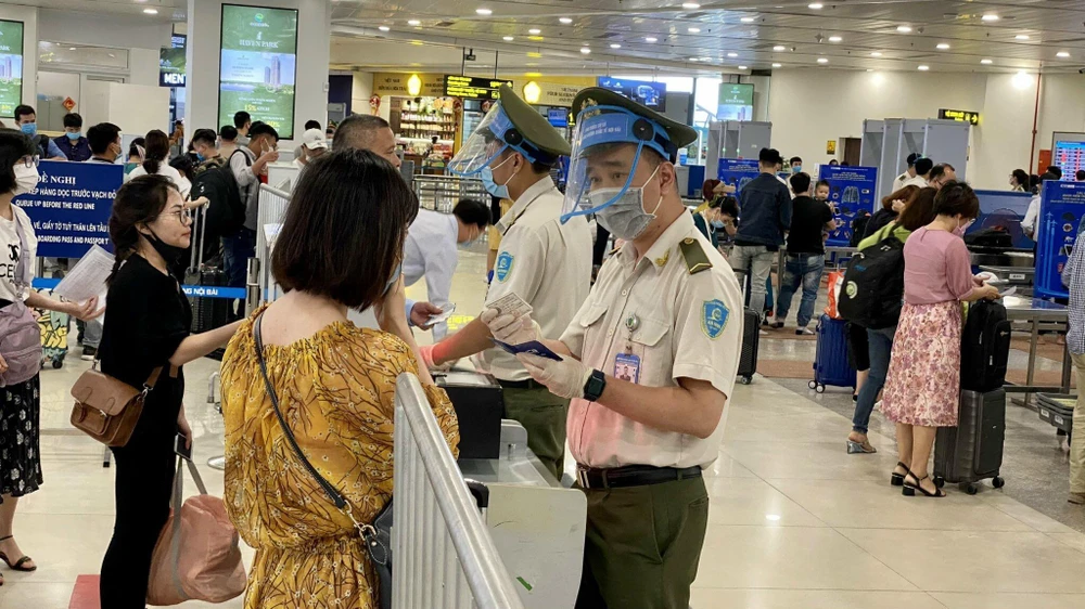 Lực lượng An ninh hàng không Nội Bài được trang bị đầy đủ găng tay, khẩu trang, tấm chắn giọt bắn trong khi tiếp xúc với hành khách. (Ảnh: CTV/Vietnam+)