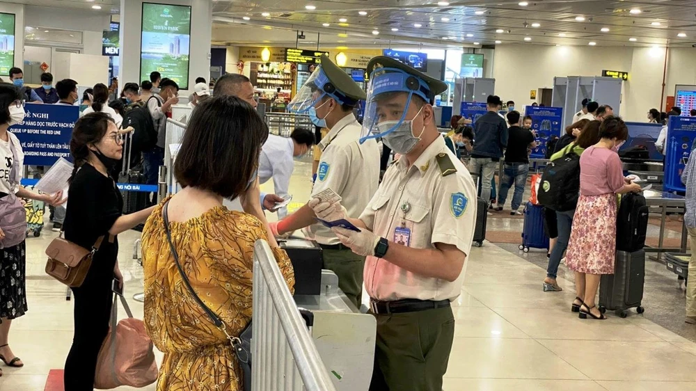 Lưc lượng an ninh hàng không tại sân bay Nội Bài kiểm soát thông tin hàng khách trước khi vào khu vực soi chiếu. (Ảnh: CTV/Vietnam+)