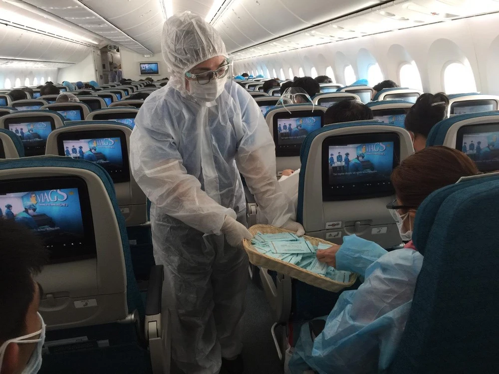 Tiếp viên Vietnam Airlines cung cấp khăn lau tay kháng khuẩn chứa cồn cho hành khách để tăng cường sát khuẩn. (Ảnh: CTV/Vietnam+)