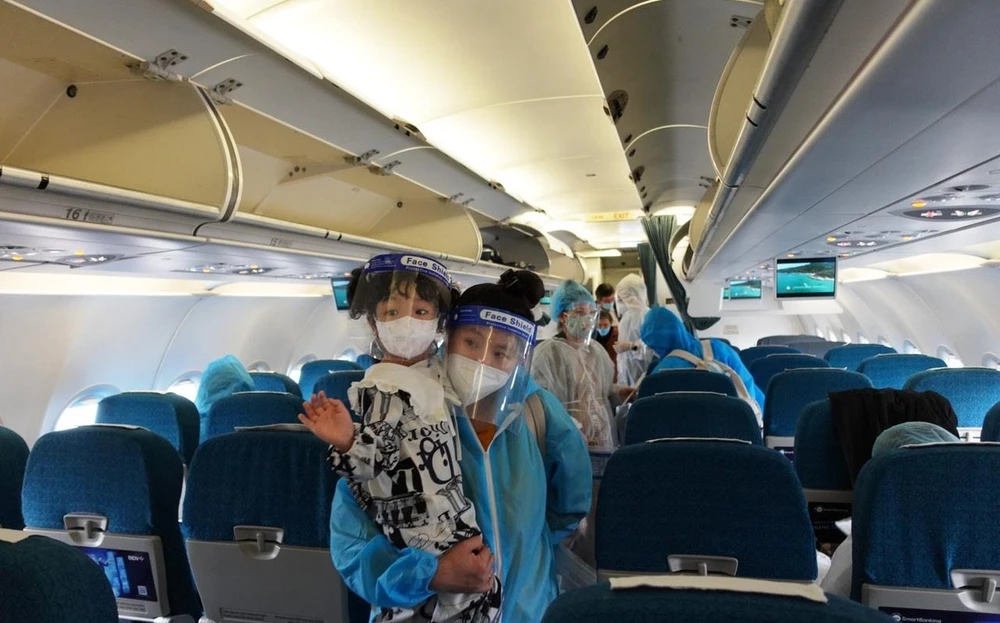Hành khách trên chuyến bay của Vietnam Airlines đưa 200 người dân Quảng Nam từ Thành phố Hồ Chí Minh hồi hương. (Ảnh: CTV/Vietnam+)