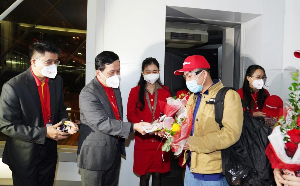 Giám đốc Điều hành Vietjet Đinh Việt Phương tặng hoa và lì xì may mắn cho hành khách trên chuyến bay đầu tiên của năm mới. (Ảnh: CTV/Vietnam+)