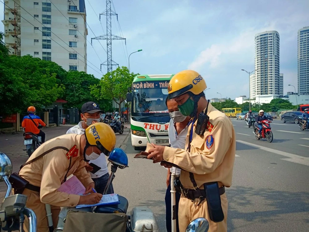 Lực lượng Cảnh sát giao thông xử phạt chủ phương tiện xe khách vi phạm giao thông. (Ảnh: PV/Vietnam+)