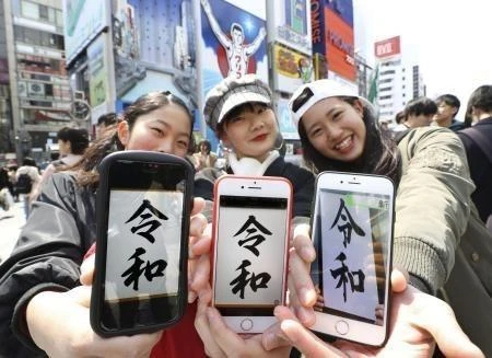 Các cô gái giới thiệu tên niên hiệu mới của Nhật Bản trên màn hình điện thoại ở Osaka ngày 1/4. (Ảnh: Kyodo/TTXVN) 