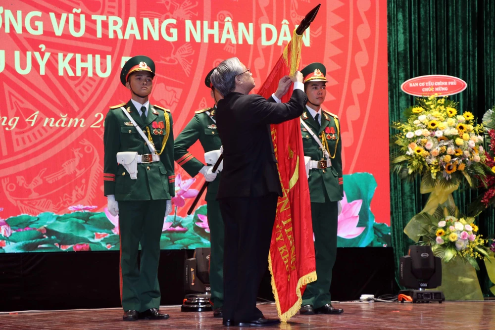 Thường trực Ban Bí thư Trần Quốc Vượng gắn danh hiệu Anh hùng Lực lượng vũ trang nhân dân lên Cờ truyền thống của Văn phòng Khu ủy Khu 5. (Ảnh: Nguyễn Sơn-TTXVN)