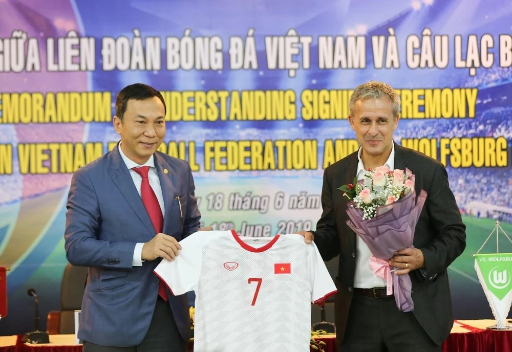 Ông Trần Quốc Tuấn; Phó Chủ tịch thường trực VFF (trái) tặng áo đấu của Đội tuyển Việt Nam cho ông Pierre Michael Littbarski, huyền thoại bóng đá Đức, Đại sứ CLB Wolfsburg. (Ảnh: Trọng Đạt/TTXVN)