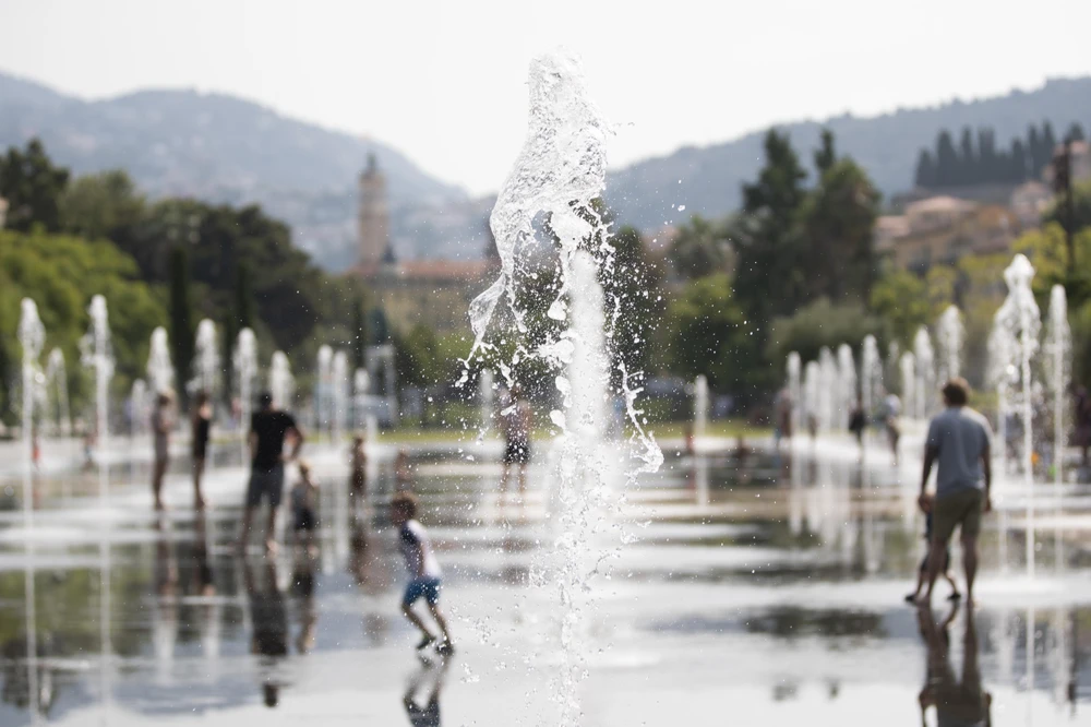 Người dân chơi đùa bên vòi phun nước để tránh nắng nóng tại Nice, miền nam nước Pháp ngày 22/7/2019. (Ảnh: THX/TTXVN)