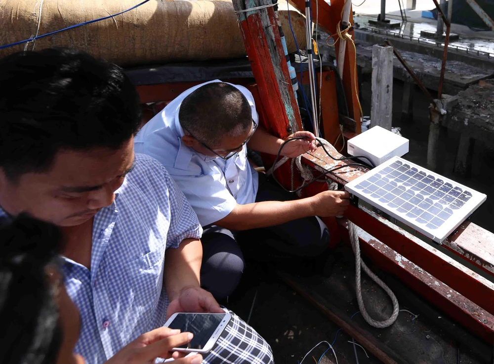 Thanh tra ngành thủy sản kiểm tra thiết bị giám sát hành trình khai thác thủy hải sản lắp đặt trên tàu cá của ngư dân. (Ảnh: Vũ Sinh/TTXVN)