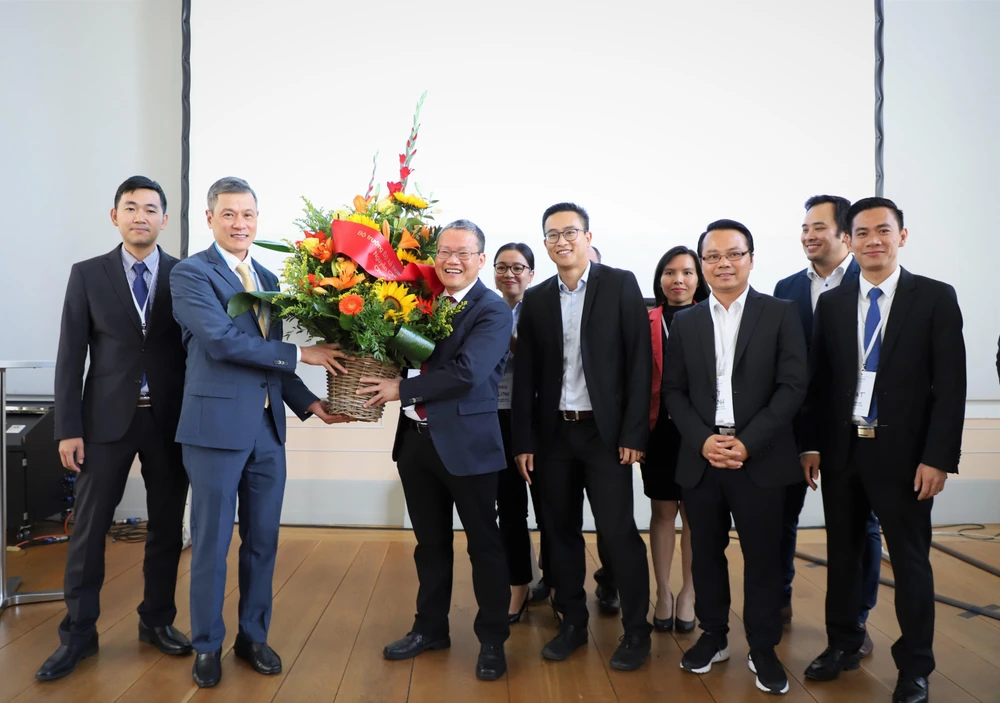 Đại sứ Việt Nam tại Đức Nguyễn Minh Vũ (trái) trao lẵng hoa chúc mừng Ban trù bị Mạng lưới Đổi mới sáng tạo Việt Đức - VGI Network. (Ảnh: Thanh Bình/TTXVN)