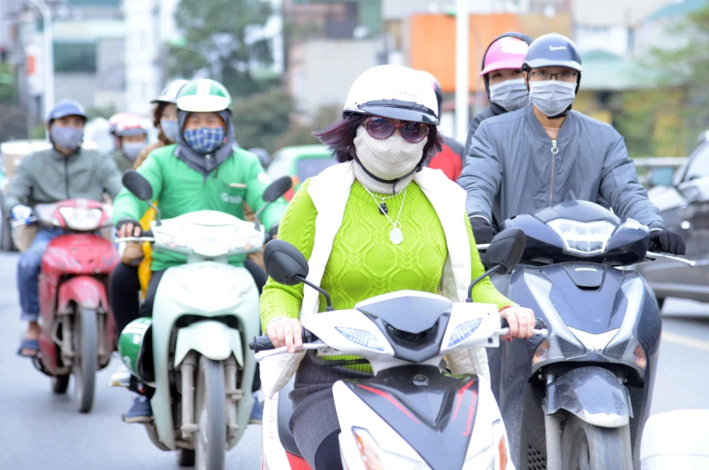 Người dân tại Hà Nội ra đường đều trang bị cho mình quần áo ấm, quấn khăn, đeo khẩu trang… để chống lại thời tiết lạnh buốt. (Ảnh: Quang Quyết/TTXVN)