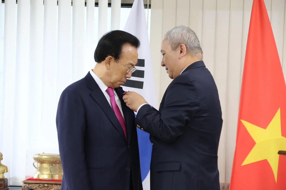 Đại sứ Việt Nam tại Hàn Quốc Nguyễn Vũ Tú trao Huân chương Lao động hạng Bacho ông Kim Kwan Yong. (Ảnh: Mạnh Hùng/TTXVN)