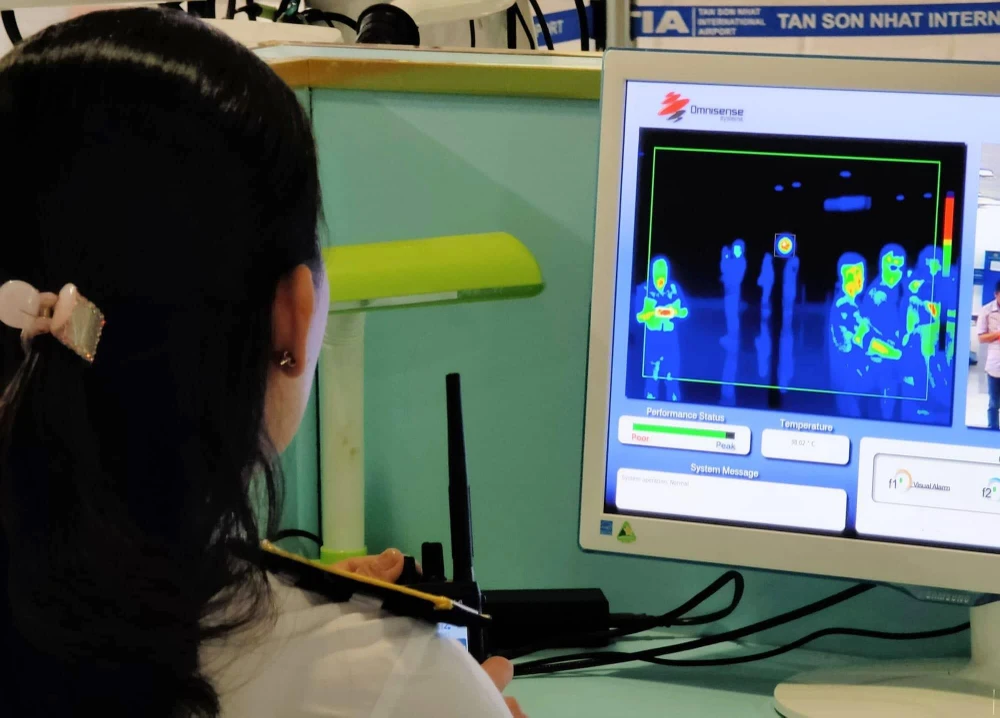 Nhân viên sân bay Tân Sơn Nhất kiểm tra màn hình hiển thị máy quét thân nhiệt đối với hành khách quốc tế đến Việt Nam. (Ảnh: Đinh Hằng/TTXVN)