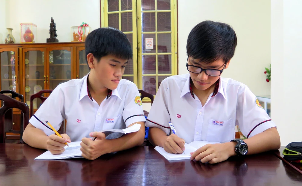 Hai anh em Tống Phước Thanh Bình và Tống Phước Thanh An (người đeo kính) trao đổi bài trước giờ lên lớp. (Ảnh: Tường Vi/TTXVN)