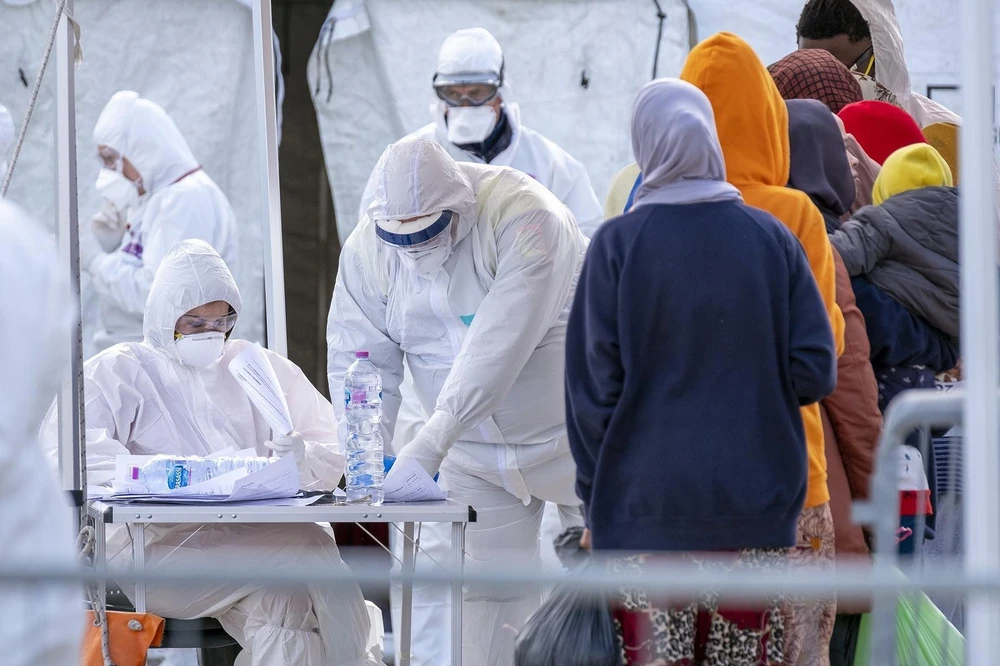 Nhân viên Hội Chữ thập đỏ Italy trong trang phục bảo hộ chống virus SARS-CoV-2 khi tiếp nhận người di cư được giải cứu trên Địa Trung Hải tại khu cảng ở Messina, Sicily ngày 27/2/2020. (Ảnh: AFP/TTXVN)