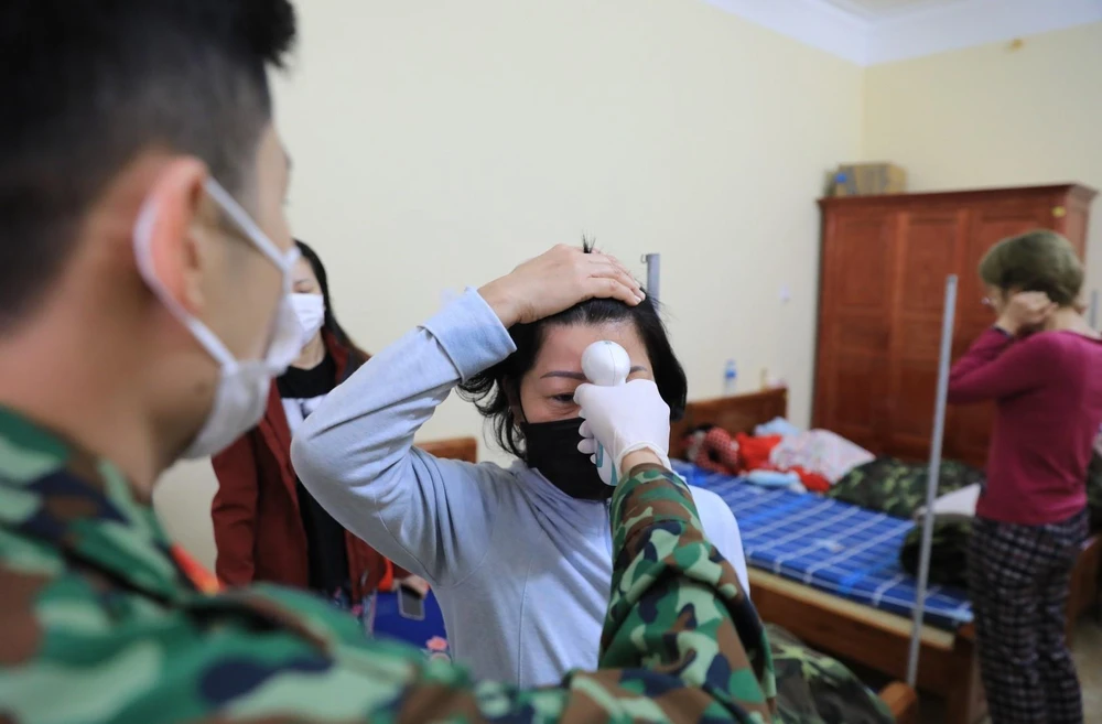 Kiểm tra nhiệt độ thân nhiệt cho từng người trong khu cách ly tập trung trường quân sự Quảng Ninh.( Ảnh: Thành Đạt/TTXVN)