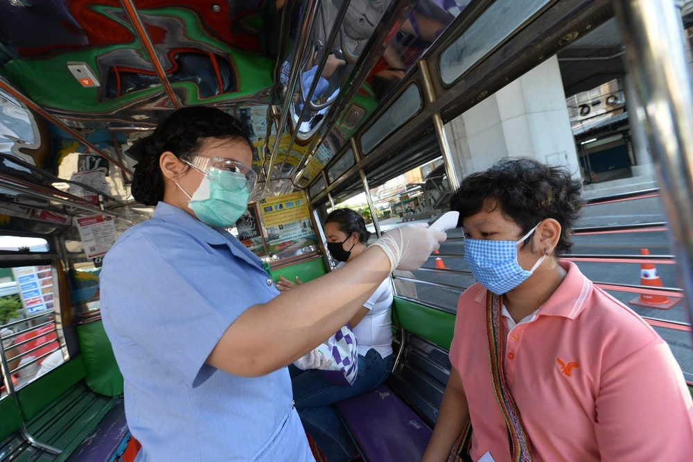 Nhân viên kiểm tra thân nhiệt của người dân tại một trạm kiểm soát ở Bangkok, Thái Lan ngày 26/3/2020, trong nỗ lực ngăn chặn sự lây lan của dịch COVID-19. (Ảnh: THX/TTXVN)