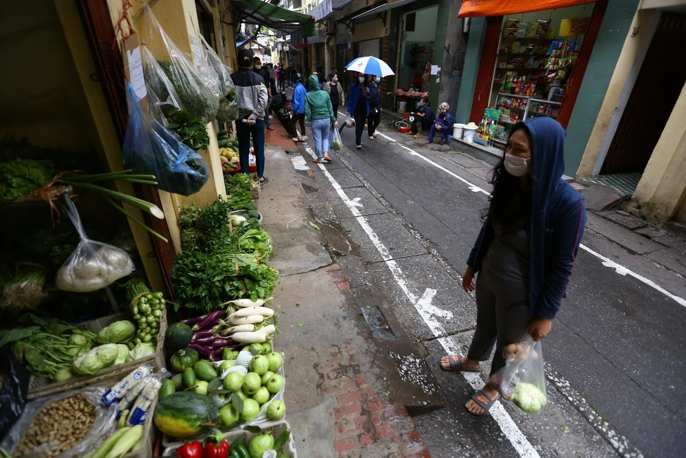 Tại những khu chợ dân sinh ở Hà Nội, đường phố được kẻ vạch sơn, quy định khoảng cách giữa người mua và người bán. (Ảnh: Minh Quyết - TTXVN)