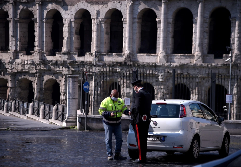Cảnh sát Italy kiểm tra giấy tờ một lái xe tại Rome, ngày 8/4/2020 khi lệnh phong tỏa toàn quốc được thực thi nhằm ngăn dịch COVID-19. (Ảnh: AFP/TTXVN)