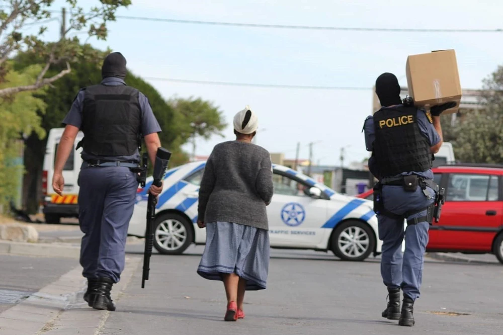 Cảnh sát Nam Phi mang hàng hóa cho một cụ già trên đường đi chợ về. (Ảnh: TTXVN phát)