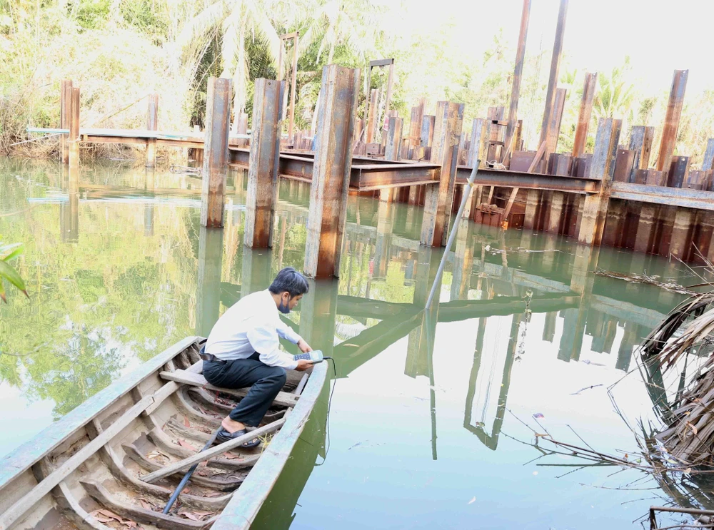 Cán bộ kỹ thuật của Sở Nông nghiệp và Phát triển nông thôn kiểm tra đo độ mặn tại đập ngăn mặn tạm thời trên sông Hàm Luông, xã Đông Sơn, thành phố Bến Tre. (Ảnh: Vũ Sinh/TTXVN)