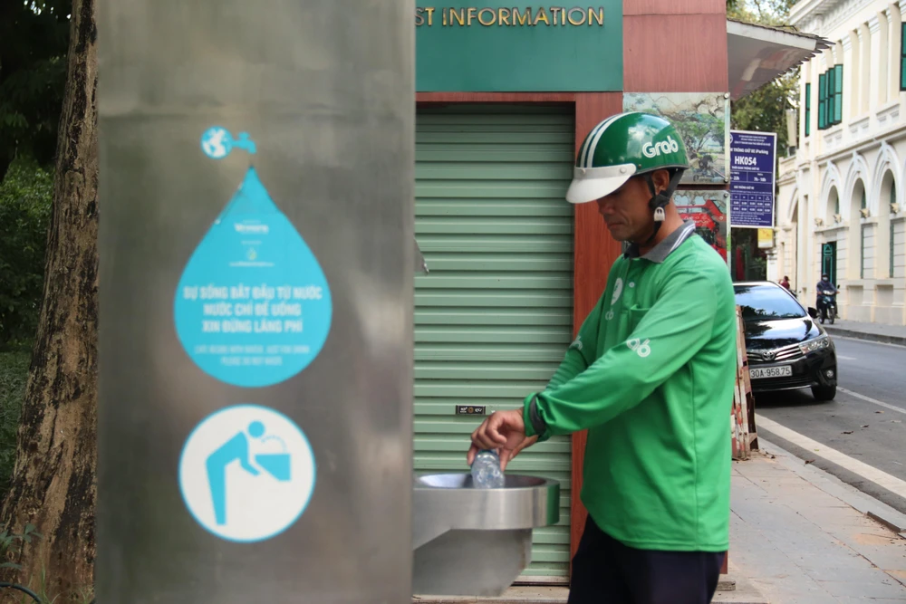 Người dân sử dụng nước ở trụ nước sạch miễn phí được đặt tại quận Hoàn Kiếm (Hà Nội). (Ảnh: Mạnh Khánh/TTXVN)