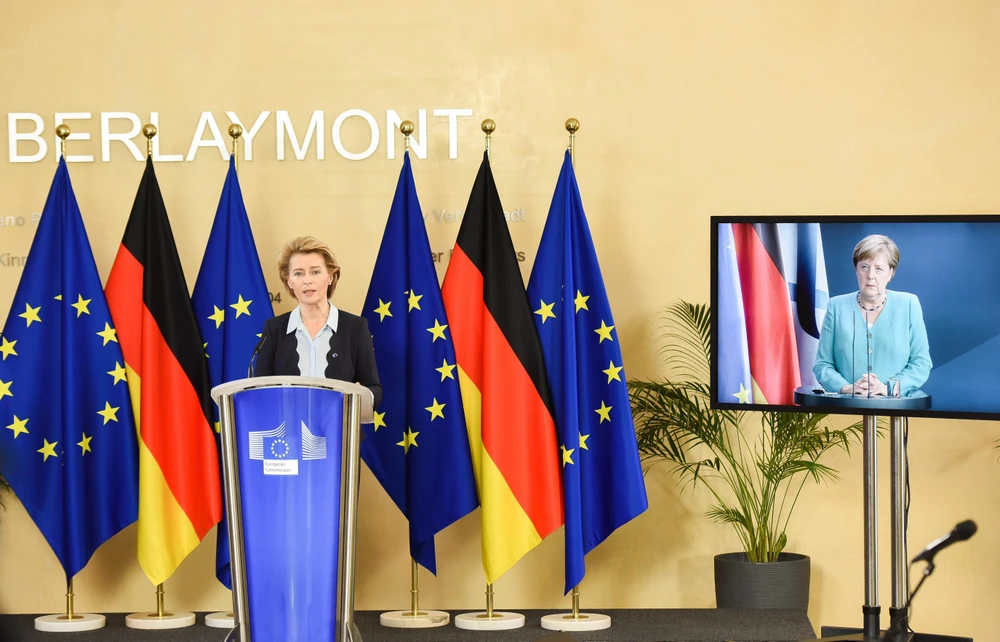 Chủ tịch Ủy ban châu Âu (EC) Ursula von der Leyen (trái) ở Brussels (Bỉ) trong cuộc thảo luận trực tuyến với Thủ tướng Đức Angela Merkel (trên màn hình). (Ảnh: THX/TTXVN)
