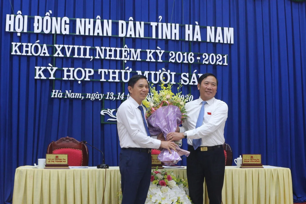 Ông Phạm Sỹ Lợi, Phó Bí thư thường trực Tỉnh ủy, Chủ tịch HĐND tỉnh Hà Nam tặng hoa chúc mừng ông Trần Xuân Dưỡng. (Ảnh: Thanh Tuấn/TTXVN)