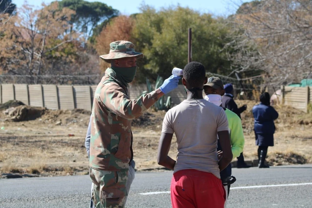 Bính lính Nam Phi thực hiện đo thân nhiệt cho người dân tại ngoại ô thủ đô Pretoria. (Ảnh: Phi Hùng/TTXVN)