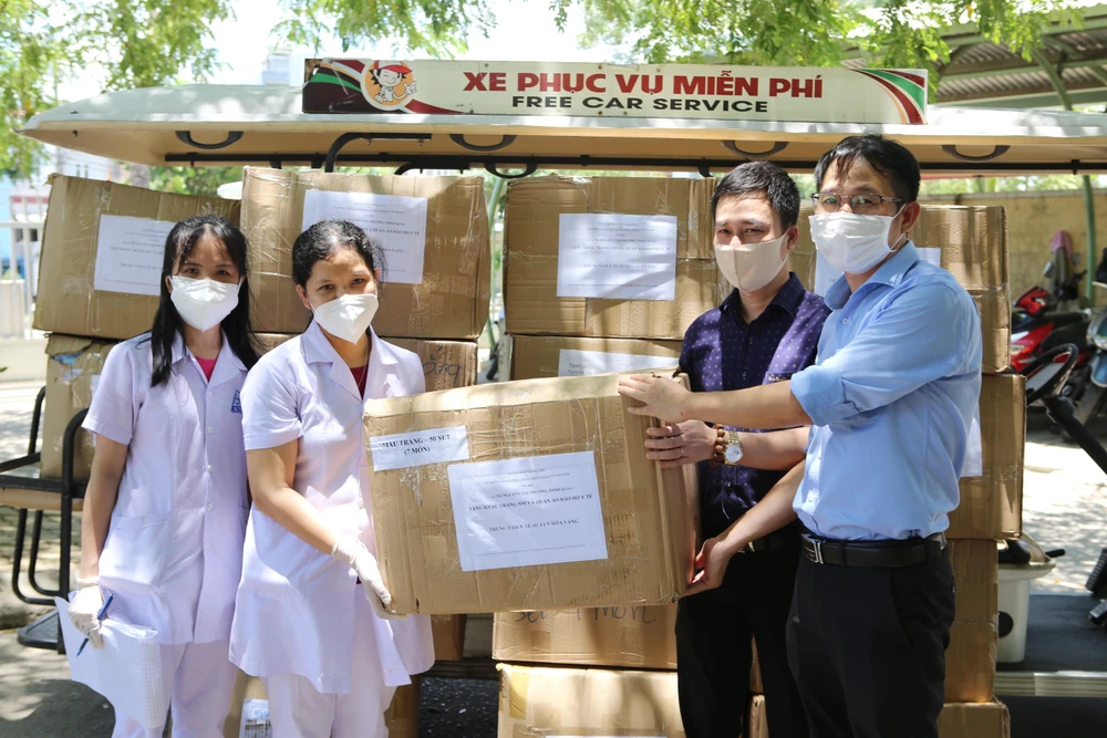 Đại diện Trung tâm Truyền hình Thông tấn và Cơ quan Thông tấn xã Việt Nam Khu vực miền Trung-Tây Nguyên tại Đà Nẵng trao tặng các thùng khẩu trang N95 và đồ bảo hộ y tế cho Trung tâm y tế huyện Hòa Vang. (Ảnh: TTXVN)