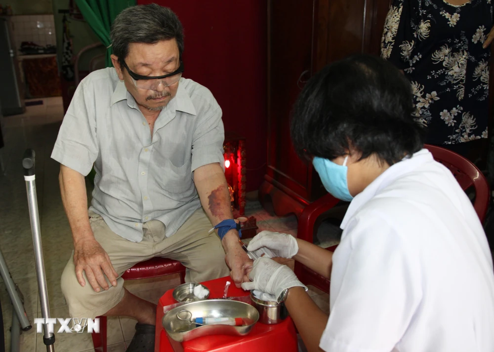 Điều dưỡng Trạm Y tế phường 16, quận Gò Vấp đến nhà lấy máu xét nghiệm cho người bệnh. (Ảnh: Đinh Hằng/TTXVN)