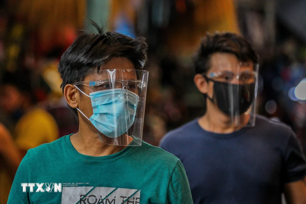 Người dân đeo khẩu trang và mặt nạ bảo hộ phòng lây nhiễm COVID-19 tại Manila, Philippines. (Ảnh: THX/TTXVN)