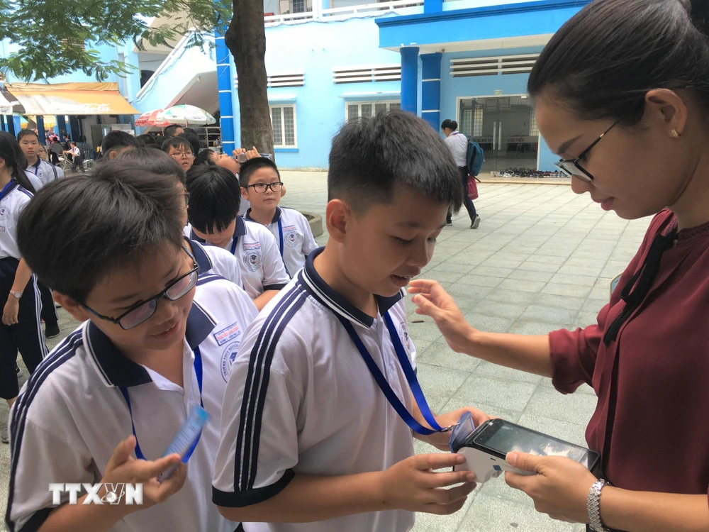 Học sinh Trường Trung học cơ sở Nguyễn Gia Thiều (quận Tân Bình) sử dụng thẻ để nhận suất ăn bán trú. (Ảnh: TTXVN phát)