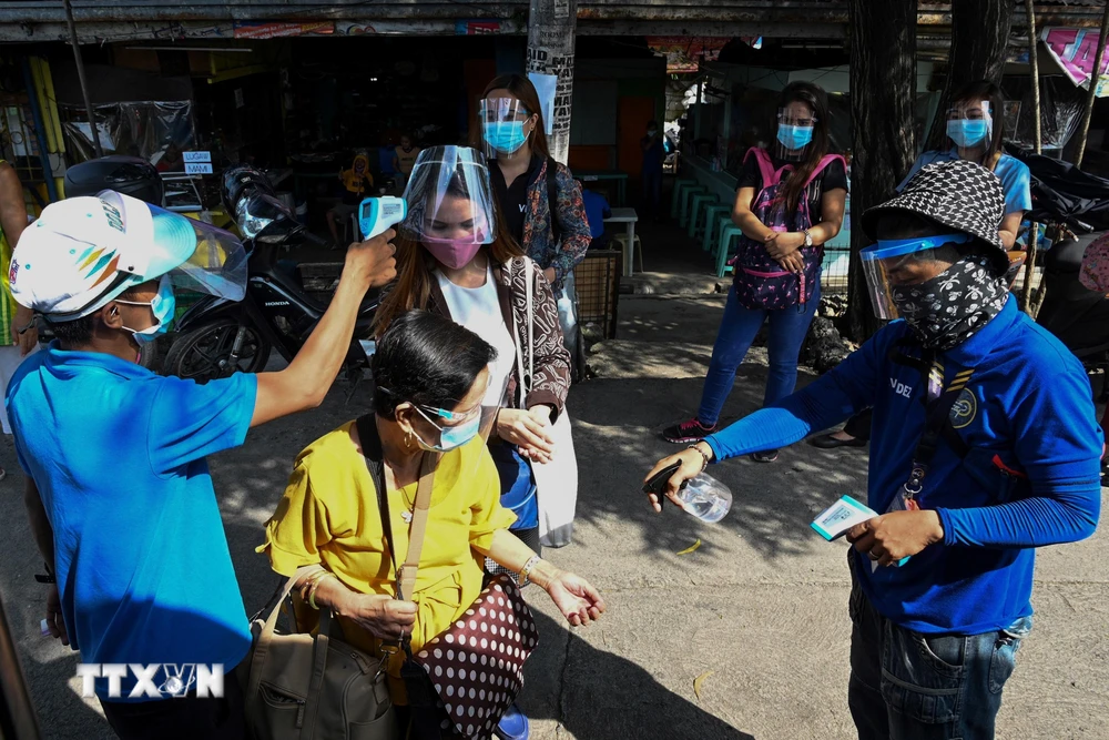 Đo thân nhiệt nhằm ngăn chặn sự lây lan của dịch COVID-19 trước khi lên xe buýt ở Manila, Philippines. (Ảnh: AFP/TTXVN)