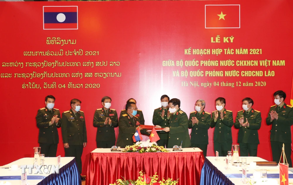 Bộ trưởng Bộ Quốc phòng Ngô Xuân Lịch và Bộ trưởng Bộ Quốc phòng Lào Chansamone Chanyalath trao đổi Kế hoạch hợp tác năm 2021 giữa Bộ Quốc phòng hai nước. (Ảnh: Hồng Pha/TTXVN phát)