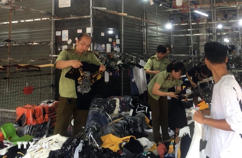 Lực lượng chức năng kiểm tra một cửa hàng kinh doanh quần áo tại chợ Ninh Hiệp. (Ảnh: TTXVN phát)