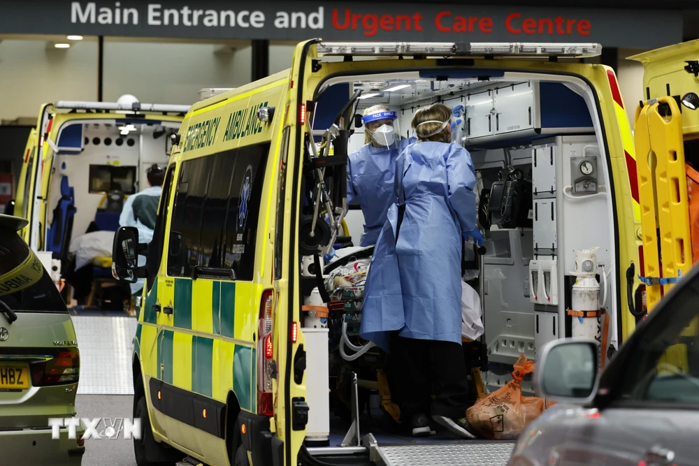 Nhân viên y tế chuyển bệnh nhân COVID-19 tới bệnh viện tại London, Anh. (Ảnh: AFP/TTXVN)