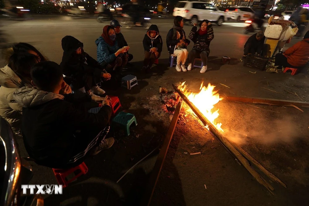 Người dân quây quần bên đống lửa để sưởi ấm trong ngày Đông giá rét. (Ảnh: Phan Tuấn Anh/TTXVN)