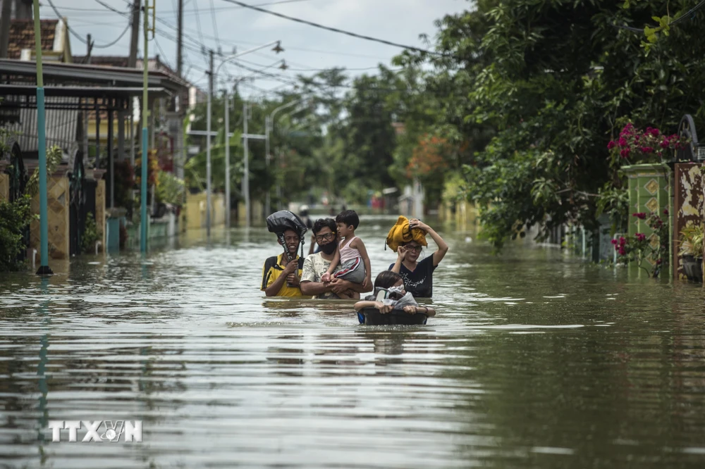 Người dân Indonesia sơ tán khỏi khu vực ngập lụt ở Gresik, Đông Java ngày 15/12/2020. (Ảnh: AFP/TTXVN)