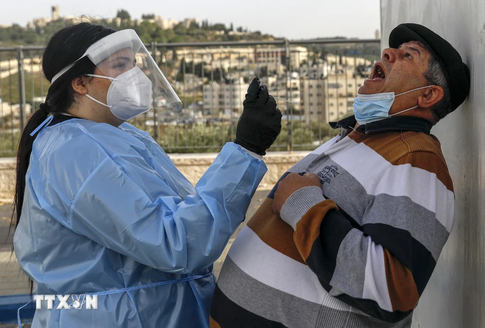 Nhân viên y tế Israel lấy mẫu xét nghiệm COVID-19 cho người dân tại Jerusalem ngày 14/12/2020. (Ảnh: AFP/TTXVN)