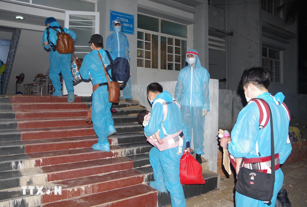 Công dân Việt Nam từ nước ngoài trở về được các nhân viên y tế hướng dẫn vào khu cách ly. (Ảnh: Chanh Đa/TTXVN)