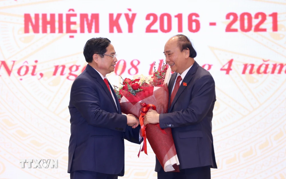 Thủ tướng Phạm Minh Chính tặng hoa chúc mừng Chủ tịch nước Nguyễn Xuân Phúc. (Ảnh: Dương Giang/TTXVN)